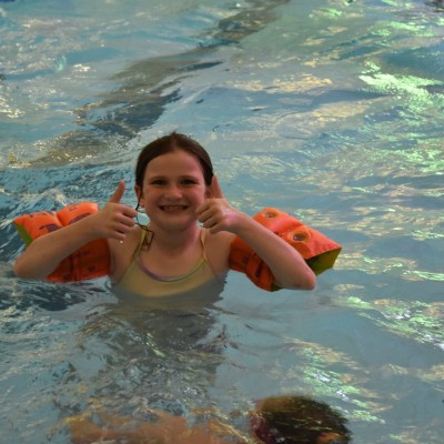 Girl putting thumbs up in swimming pool
