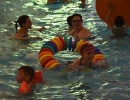 Girl playing with a floating ring in swimming pool surrounded by swimmers