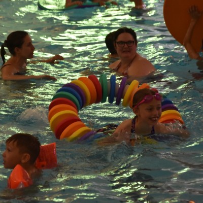 Girl playing with a floating ring in swimming pool surrounded by swimmers